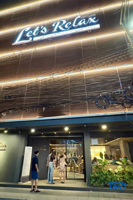 The exterior of Let's Relax Spa in Bangkok, showing the large illuminated sign and entrance to the popular wellness center. Original photo by Ariana of WinterExpat.