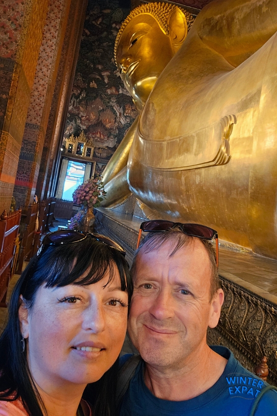 Ariana and Z taking a selfie beside the giant golden Reclining Buddha inside Wat Pho Temple in Bangkok, Thailand. Original photo by Ariana of WinterExpat.