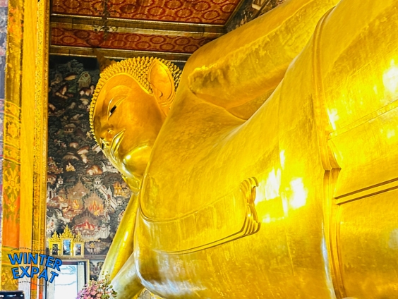Golden Reclining Buddha inside Wat Pho with the text "Wat Pho Reclining Buddha Guide for First Timers," showing visitors viewing one of Bangkok's most famous temple attractions. Original photo by Ariana of WinterExpat.